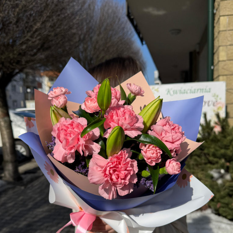 Biało różowo fioletowy bukiet z lilii, różowych goździków i limonium w papierze dekoracyjnym z kokardką